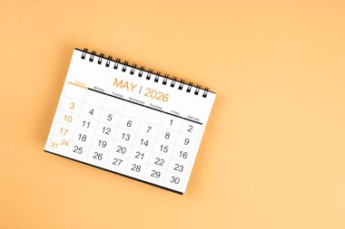 Sarı pastel arka planda Mayıs 2026 masa takviminin üst görünümü.