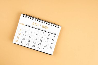 Sarı pastel arka planda Temmuz 2026 masa takviminin üst görünümü.