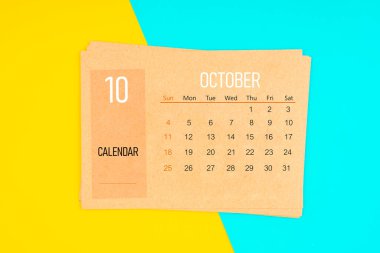 Sarı ve mavi arka planda 2026 Ekim ayı için kahverengi takvim kartı.