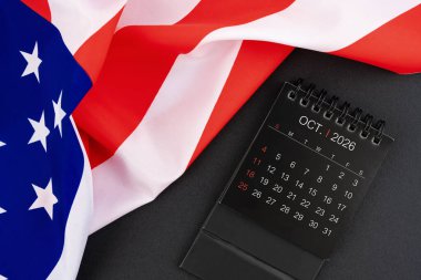 Ekim 2026 siyah renkli aylık masa takvimi ve Amerika Birleşik Devletleri bayrağı.