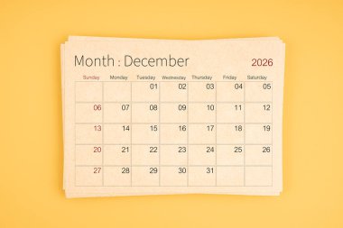 Sarı arkaplan üzerine kahverengi geri dönüşüm kağıdından Aralık 2026 takvimi.