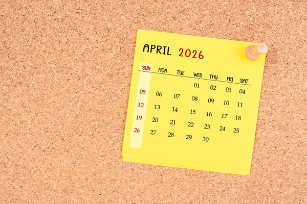 Tahta raptiyeli Nisan 2026 için sarı takvim kağıdı.