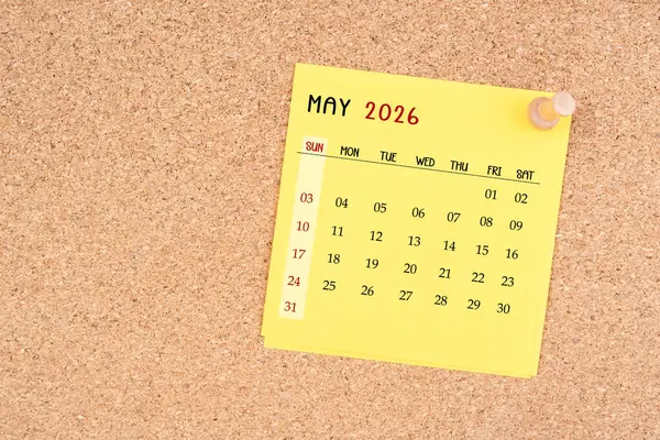 Tahta raptiyeli Mayıs 2026 için sarı takvim kağıdı.
