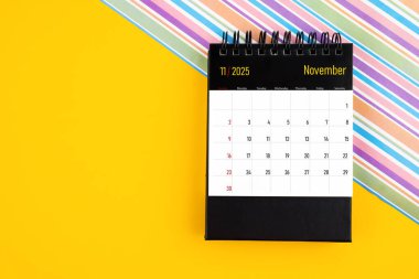 Sarı arkaplan üzerinde Kasım 2025 için masa takvimi, kopyalama alanı olan konum.