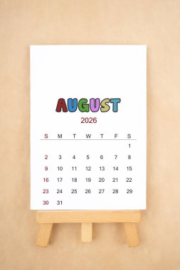 Ağustos 2026 takvim sayfası eski kahverengi arka planda ahşap sehpa ile.