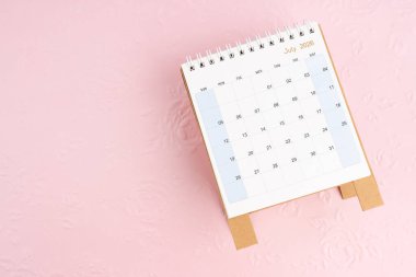 Temmuz 2026, masa takvimi pembe kağıt üzerinde çiçek desenli arkaplan, düz yatıyordu.