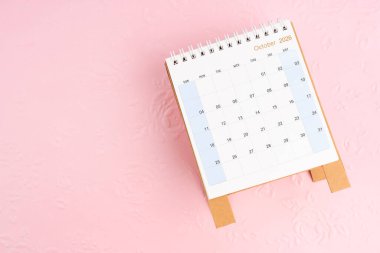 Ekim 2026, masa takvimi pembe kağıt üzerinde çiçek desenli arka plan, düz yatıyordu.