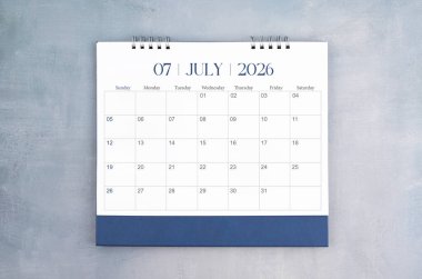 Temmuz 2026 gri çimento duvar arkaplanlı masa takvimi. Yıllık takvim sayfası.