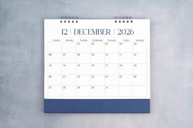 Aralık 2026 gri çimento duvar arka planında masa takvimi. Yıllık takvim sayfası.