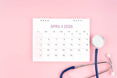 Nisan 2026 Masa takvimi ve pembe steteskop, Tıbbi randevu kavramı.