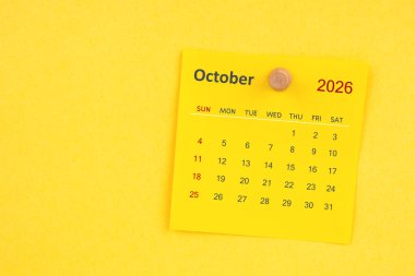 Sarı zemin üzerinde raptiye bulunan Ekim 2026 takvim sayfası.