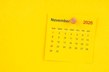 Sarı zemin üzerinde raptiye bulunan Kasım 2026 takvim sayfası.