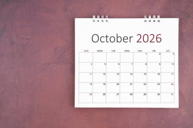 Ekim 2026 kırmızı çimento duvar arka planında masa takvimi. Yıllık takvim sayfası.