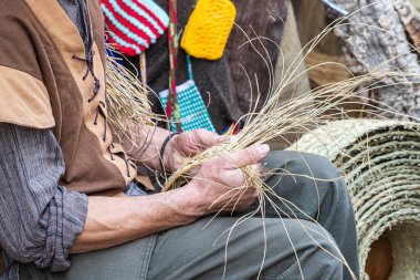 Sepet ve hasır ürünlerin nasıl yapıldığını gösteren bir sepet imalatçısının ellerinin yatay görüntüsüne yakın çekim. El sanatları kavramı