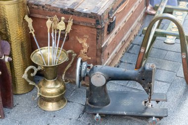 Eski ikinci el eşyaların bir dayanışma pazarında satıldığı bir açık hava sergisinde antik nesnelerin ön planı. İkinci el dayanışma pazarı