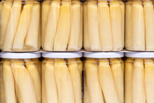 stock image close up in horizontal view of several glass jar with preserved white large asparagus. food preservation concept