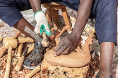 Afrika 'lı genç bir heykeltıraşın ahşap bir figürün el ele tutuşmasını yakından ve yatay olarak izledik. 