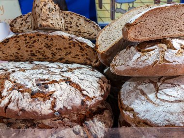 Büyük zeytin ekmeği somunlarının yatay görüntüsüne yakın çekim. Zanaatkar bir şekilde pişirilmiş ve satışa sunulmuş.