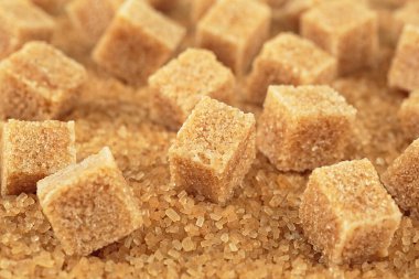 Şeker kristallerinin üzerinde kahverengi şeker küpleri, yakın çekim. Demerara altın şekeri.