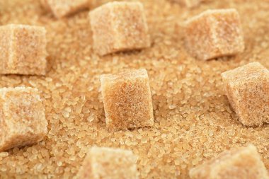 Şeker kristallerinin üzerinde kahverengi şeker küpleri, yakın çekim. Demerara altın şekeri.