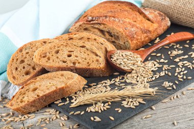 Freshly baked rye bread on wooden table. Whole grain rye baguette with seeds and spikelets.