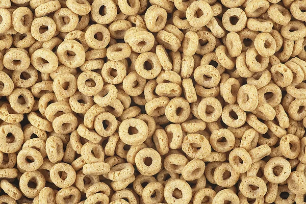 Delicious cereal rings with honey as background, top view. Breakfast cereal.