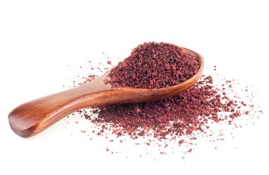 Beyaz arka planda izole edilmiş tahta kaşıkta yer sumac baharat yığını.