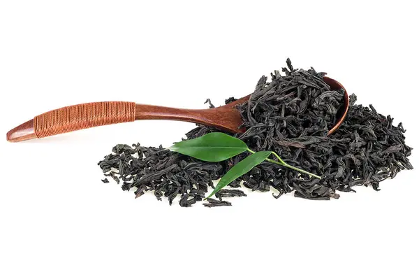木のスプーンと新鮮な紅茶の葉を白い背景に分離した乾燥黒茶葉 — ストック写真