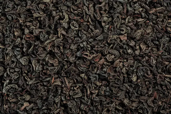 Background of dry black tea leaves with bergamot flavour, top view. Dried black tea as background. Black dry tea wallpaper.