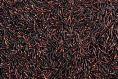 Arka plan olarak çiğ siyah pirinç, üst manzara. Kuru organik siyah pirinç taneleri. Siyah glutinous pilav, sağlıklı beslenme ve vejetaryen diyeti..