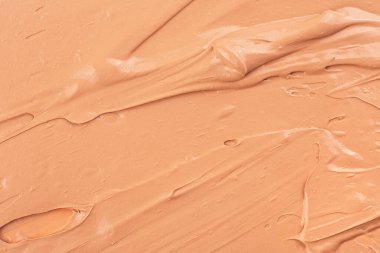 Sıvı temelden yapılmış bir arka plan. Kremalı temel dokusu. Kremsi vakfın bej makyaj lekesi. Temel kumaş dokusu.