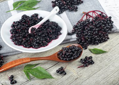 Taze olgun siyah mürver, mürver şurubu ve kırsal ahşap arka planda mürver yaprakları. Alternatif tıp ve yaşam tarzı.