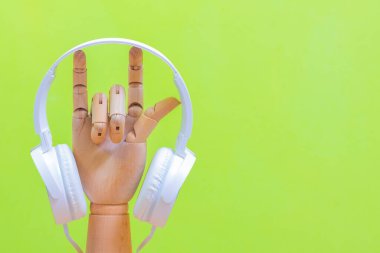 Aşk tabelasına asılı beyaz kulaklık. Pastel yeşil arka planda ahşap el modeli. müzik aşığı ya da sağlık hizmeti kavramı