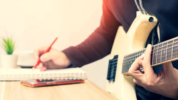 男歌手在弹白色电吉他的同时写了一首热门歌曲 歌曲写作概念 — 图库照片