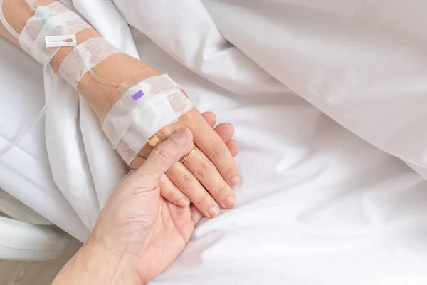 stock image close up man holding his lover hand with love and care while sick on patient bed in hospital