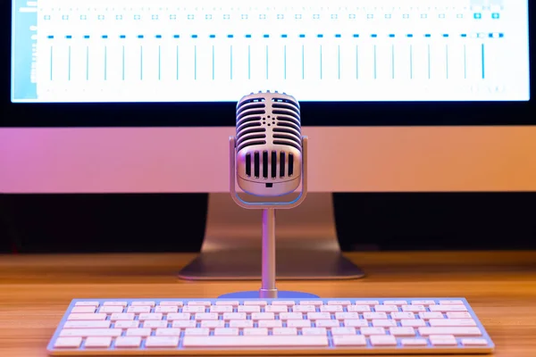 vintage microphone on desktop computer display background. recording, singing, broadcasting concept