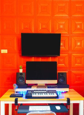 Ev stüdyosu, müzik üretimi, dijital kayıt cihazları konsepti. bilgisayar, midi klavye, hoparlörleri monitör, kırmızı emici duvarda görüntüleme