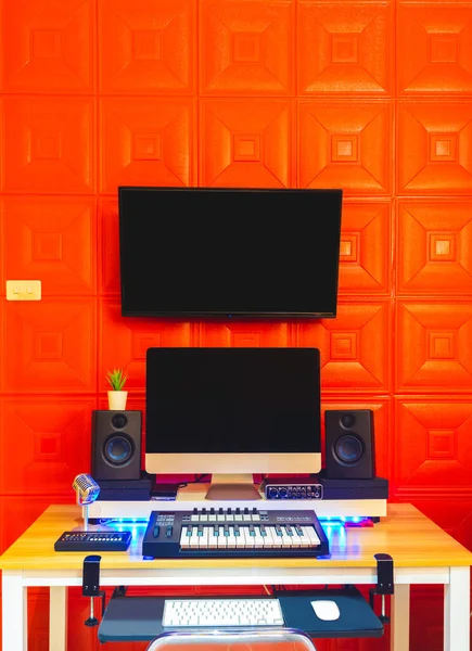 Home studio,music production, digital recording equipment concept. computer, midi keyboard, monitor speakers, display on red absorber wall