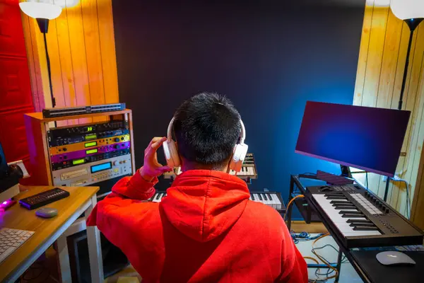 back of asian male music producer, composer, musician arranging a hit song in home studio. music production concept