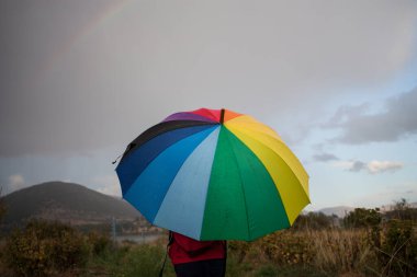 Yağmurlu bir günde Medaw 'da gökkuşağı şemsiyesi taşıyan bir çocuğun arka görüntüsü