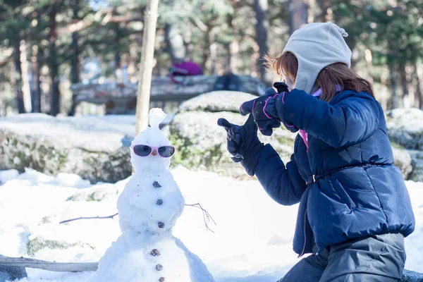 雪だるまと遊んでいる女の子 スノーウィーアウトドア ウィンター 水平に フェイスレス — ストック写真