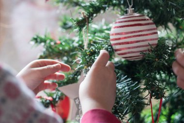 Noel ağacını süsleyen küçük çocukların elleri. Yatay olarak. Yüzsüz. Kış. İç mekan.