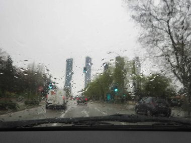 A shot of a rain-splattered window, revealing a traficc car background. View of raindrops on window clipart