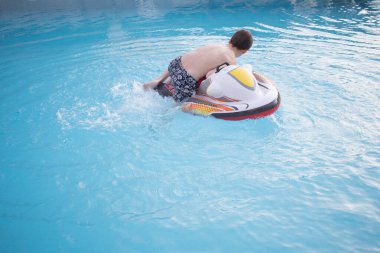 Çocuk yüzme havuzunda şişme şamandırayla oynuyor. Yatay olarak. Uzayı kopyala Yüzsüz. Yaz