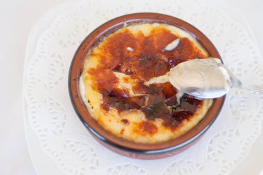 Beyaz tabak Katalan kreması (creme brulee tatlısı) ya da gümüş kaşıklı muhallebi, merkez manzara. Yatay