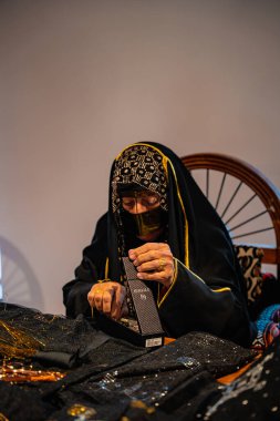 DOHA, Katar - 13 Aralık 2024: Geleneksel siyah elbiseli Katarlı bir kadın Darb Al Saai 'deki Katar Evi' nde oturuyor.