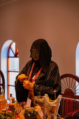 DOHA, Katar - 13 Aralık 2024: Geleneksel siyah elbiseli Katarlı bir kadın Darb Al Saai 'deki Katar Evi' nde oturuyor.