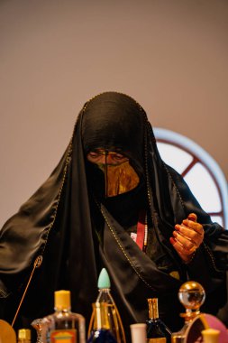 DOHA, Katar - 13 Aralık 2024: Geleneksel siyah elbiseli Katarlı bir kadın Darb Al Saai 'deki Katar Evi' nde oturuyor.