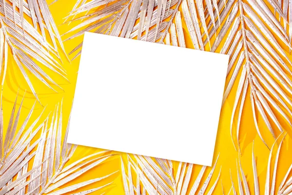 stock image Golden leaves of a palm tree and a white leaf on a yellow background. Empty space. Summer concept