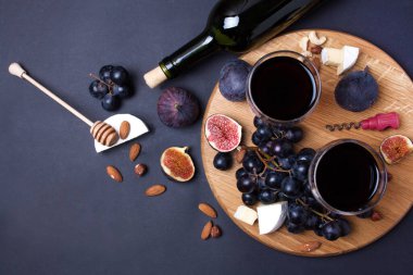 Siyah arka planda bir şişe şarap, incir ve peynir. Düz Yatma Biçimi